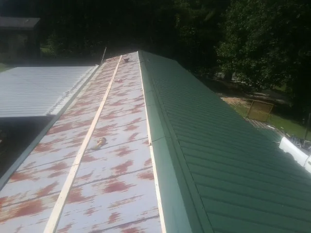 Old rusted panels beside newly installed green metal roofing — Wind Damage Roof Repair by Roofing Brothers in Faribault