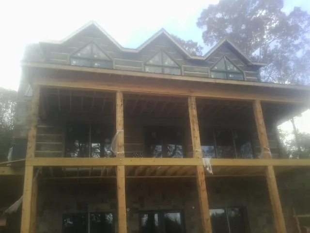 Dormers and porch framing on a large log home under construction — Roof Coating work by our crew in Faribault