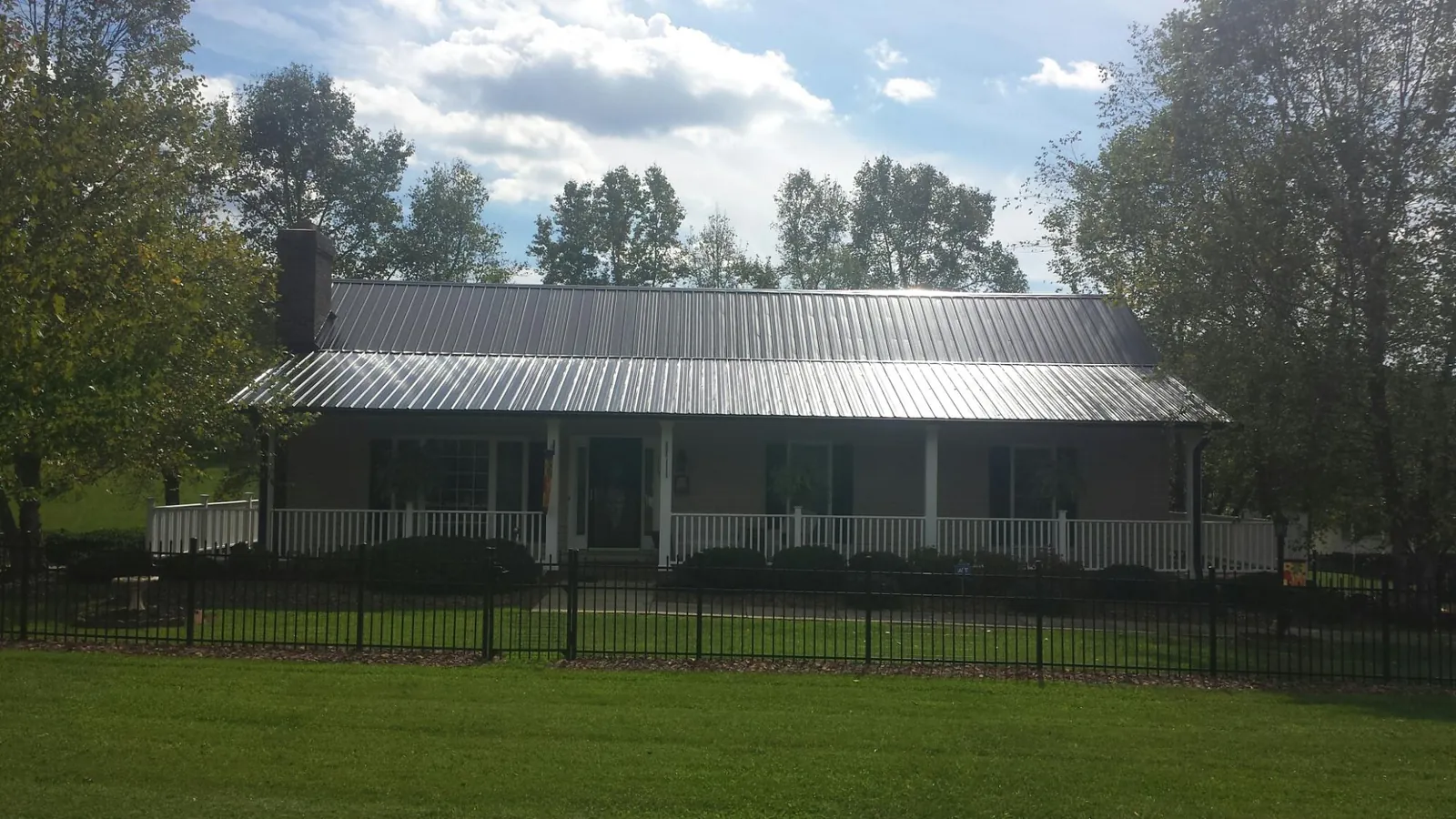 Gray metal roof on a brick ranch with a full width front porch — Gutter Guard Installation work by our crew in Faribault